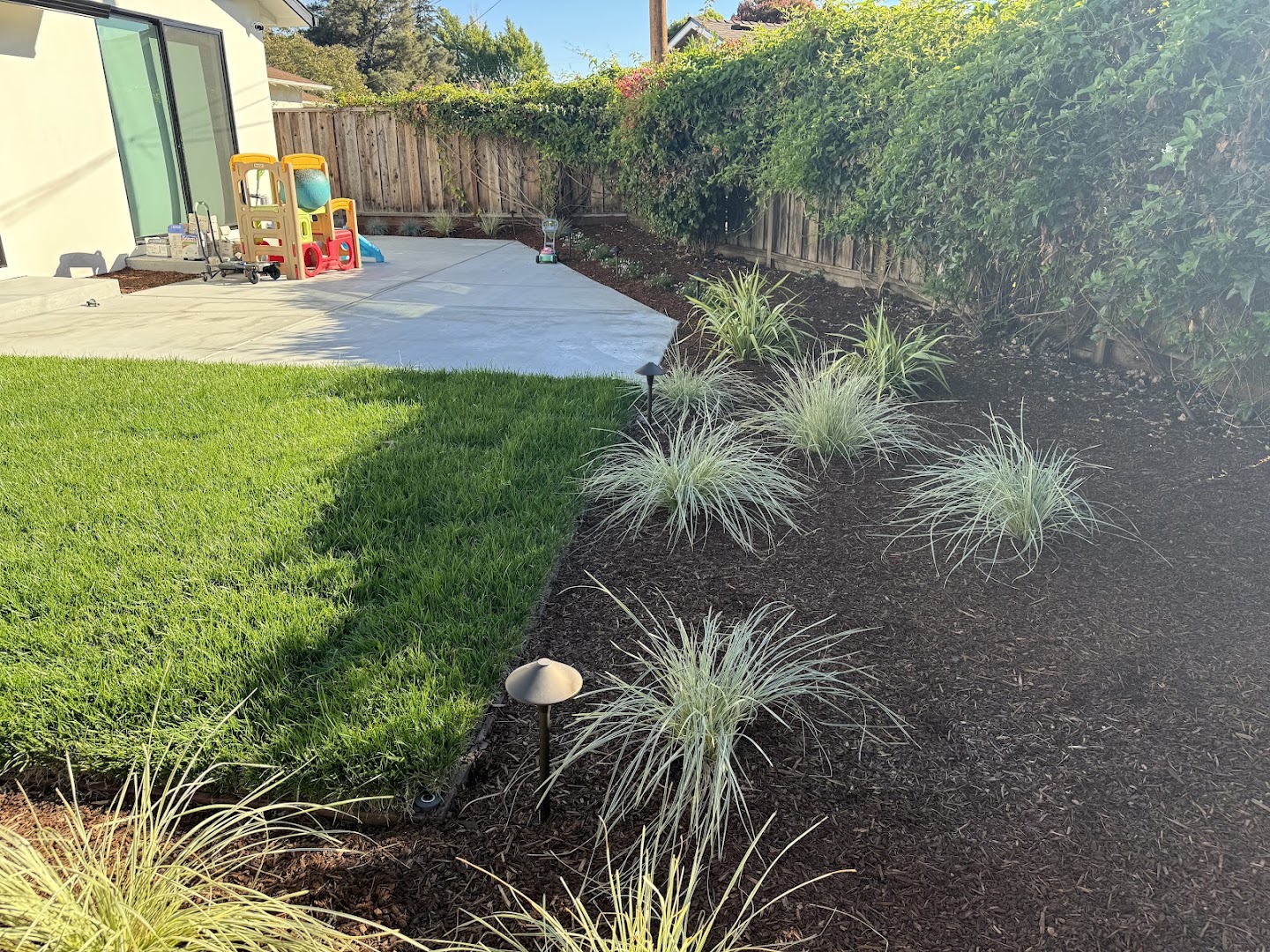 New concrete patio with fresh lawn and planting beds by PaveMasters